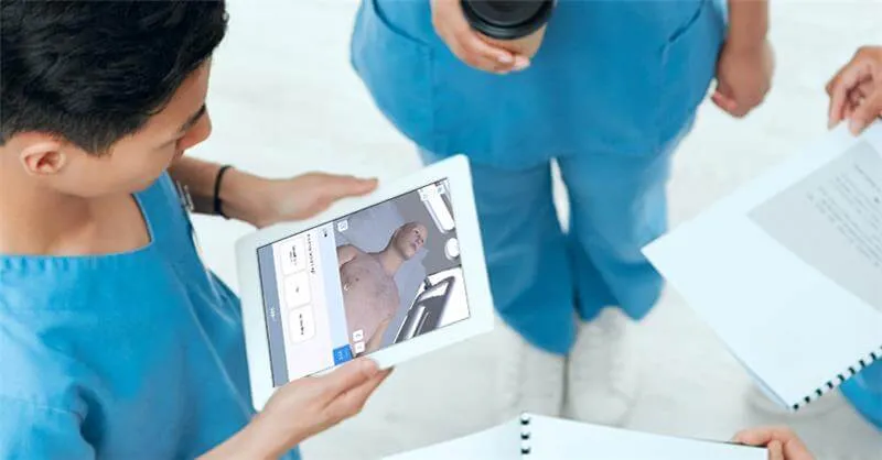 two nurses viewing a tablet displaying a simulated patient